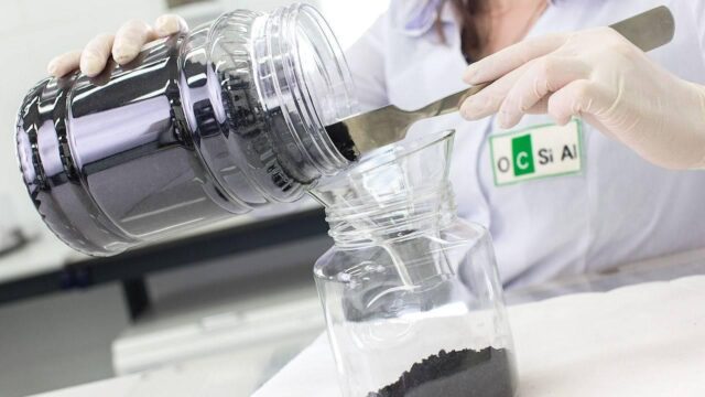 A lab worker is pouring graphene from a glass into another