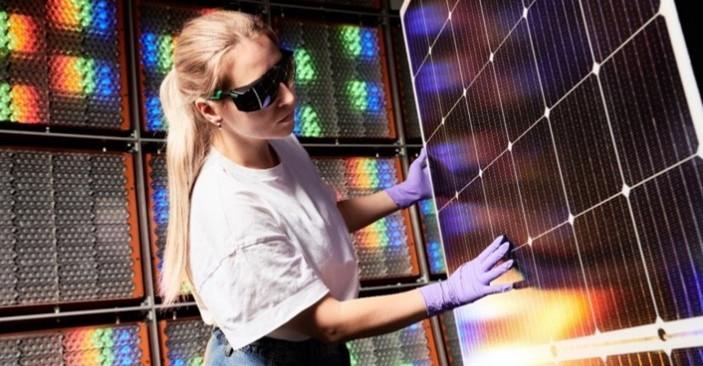 A young woman with blonde hair touching a solar panel