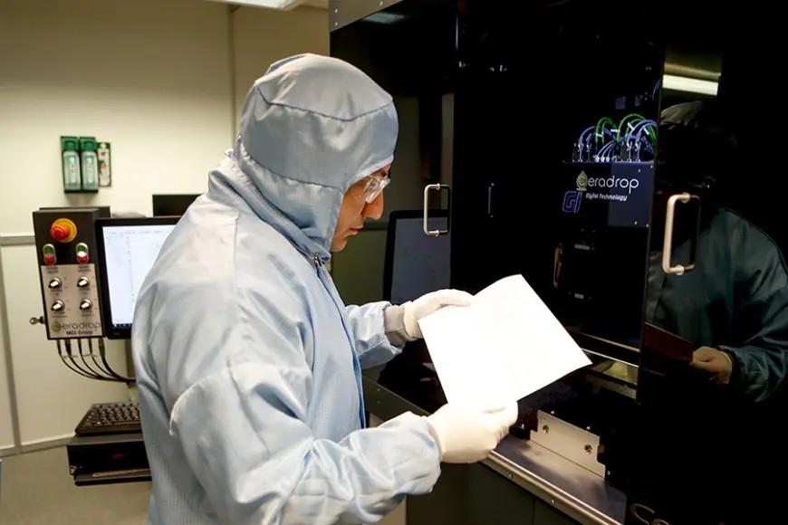 A lab worker in protective equipment in front of a Ceradrop printer