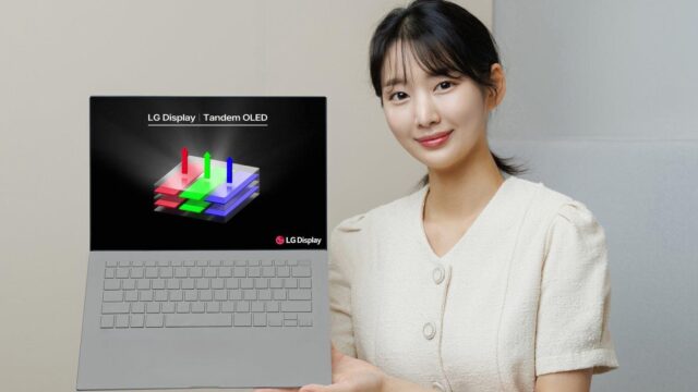 A woman holding a laptop with Tandem OLED technology