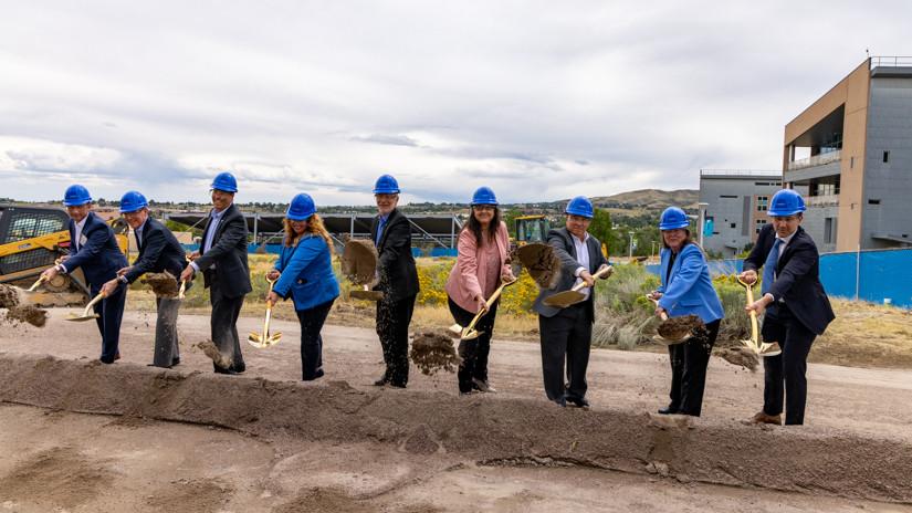 Nine people with shovels and hard hats toss dirt into a pile. The ceremonial groundbreaking of NREL's Energy Materials and Processing at Scale (EMAPS) facility