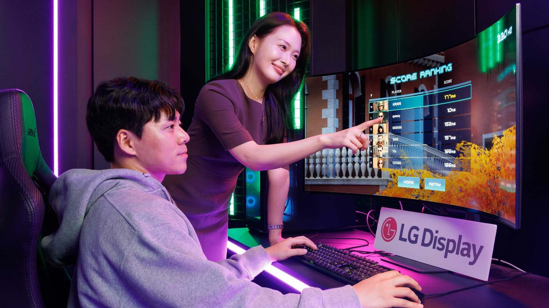 A woman and a man in front of a curved computer screen