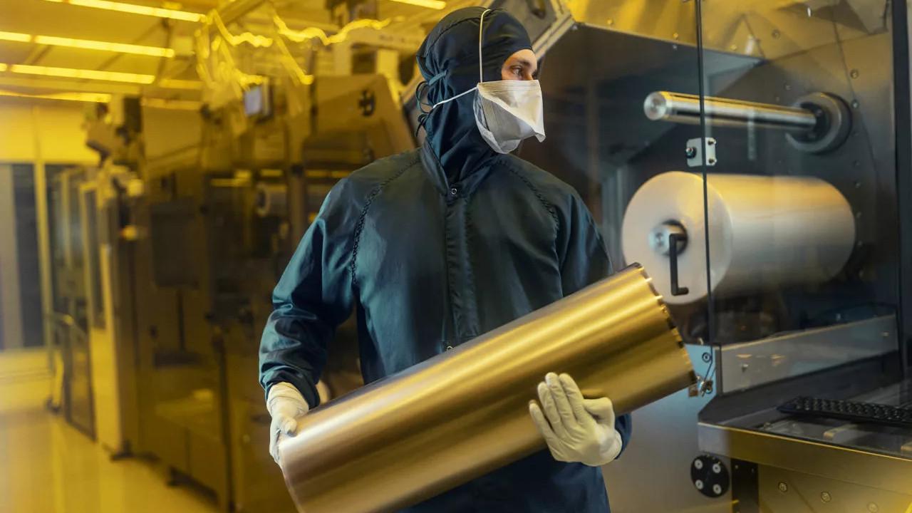 A lab worker holding a roll in a cleanroom